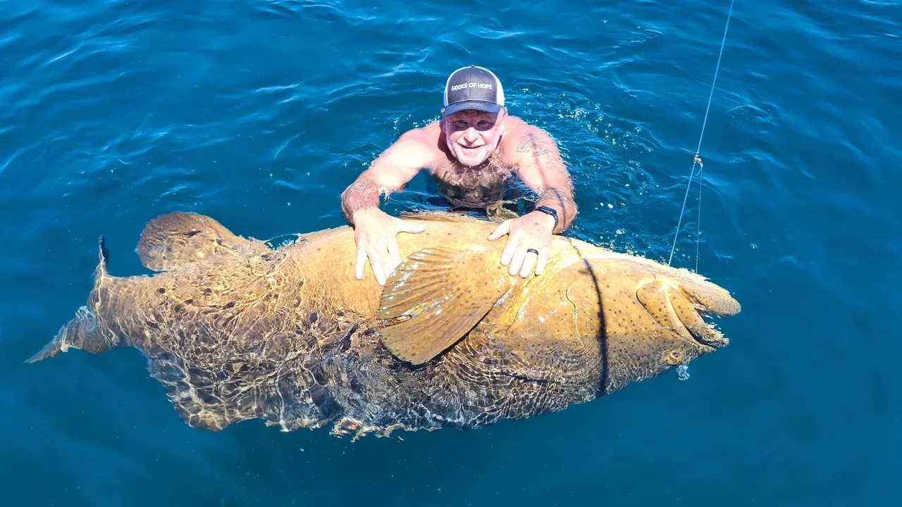 Smiling swimmer holds giant fish