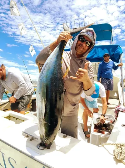Fisherman holding large tuna on boat